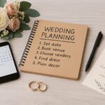 Flat lay of DIY wedding planning essentials including a spiral-bound “Wedding Planning” notebook, smartphone calendar, save-the-date card, gold wedding rings, and a small bouquet of blush and ivory roses on a light wood table. Landscape orientation and optimized for blog and Google updates.