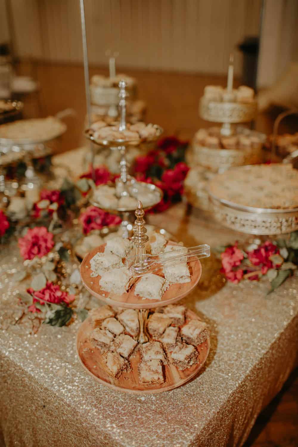 Elegant dessert table with cookies, flowers, and tiered stands for wedding or event.